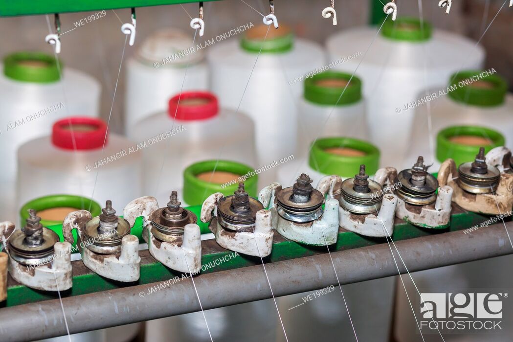 Stock Photo: Red-green spools of white yarn in a garment factory. Weaving loom in a textile factory.
