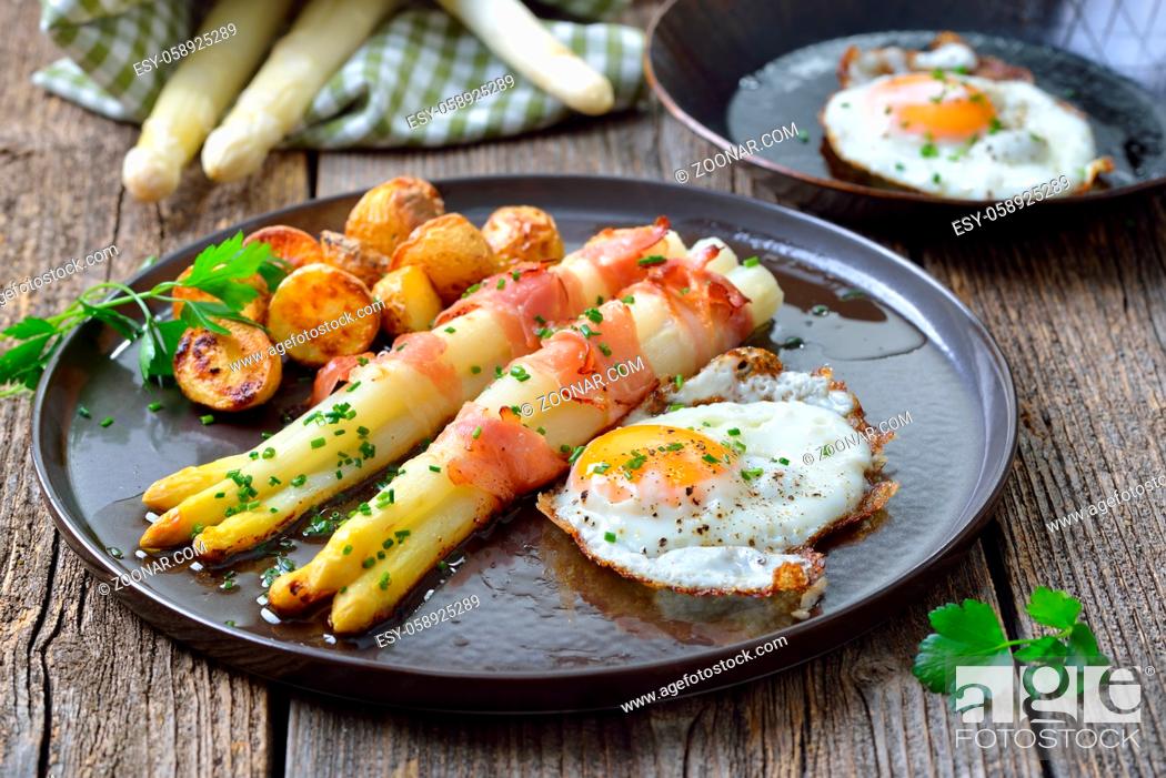 Photo de stock: Gebackener Spargel mit Speckstreifen, Ofenkartoffeln und Spiegelei ?Baked white asparagus with bacon strips, crunchy potatoes and fried eggs.