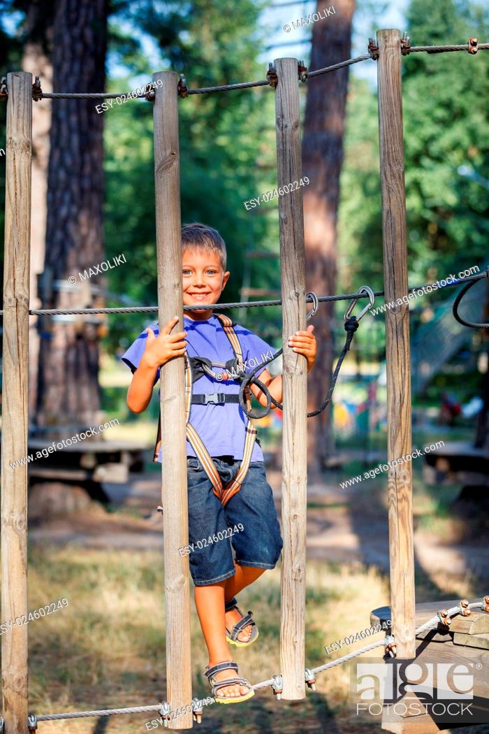 Stock Photo: Happy child, preschool boy enjoying activity in a climbing adventure park on a summer day.
