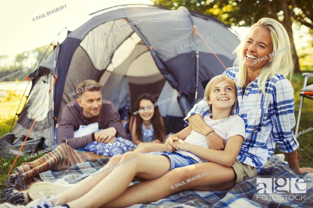 Imagen: Smiling family relaxing outside campsite tent.