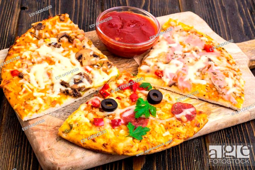Stock Photo: Three pieces of different pizzas on a wooden. Studio Photo.