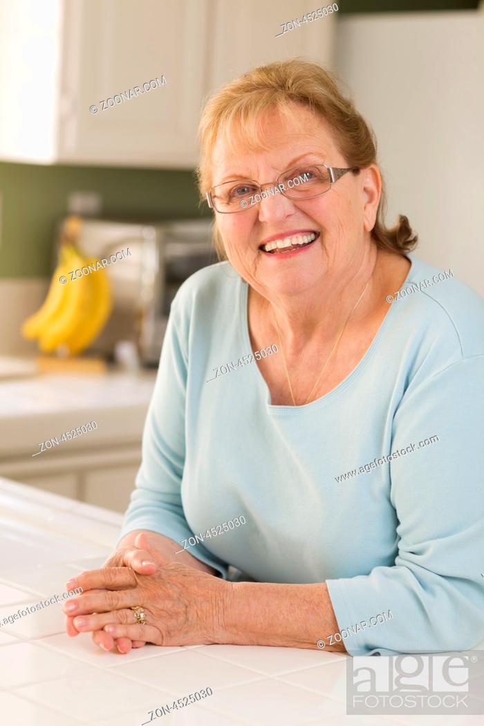 Stock Photo: Portrait of a Beautiful Smiling Senior Adult Woman in Kitchen.