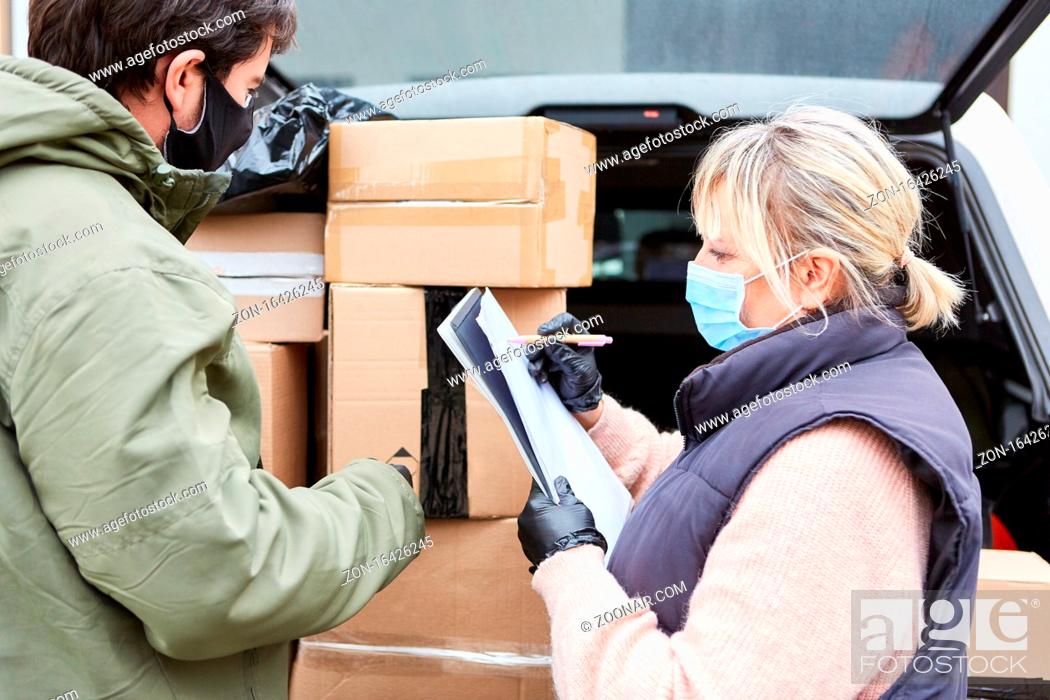 Stock Photo: Paketdienst Team prüft Lieferungen vor offenem Laderaum mit vielen Paketen.