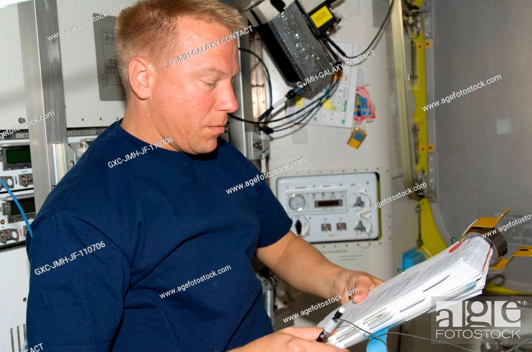 Stock Photo: Astronaut Tim Kopra, Expedition 20 flight engineer, looks over a checklist while assisting the spacewalk preparations of astronauts Dave Wolf and Christopher.