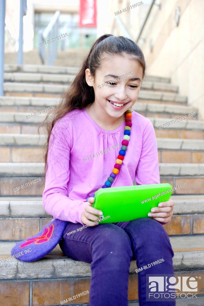 Stock Photo: Mixed race girl using digital tablet on staircase.