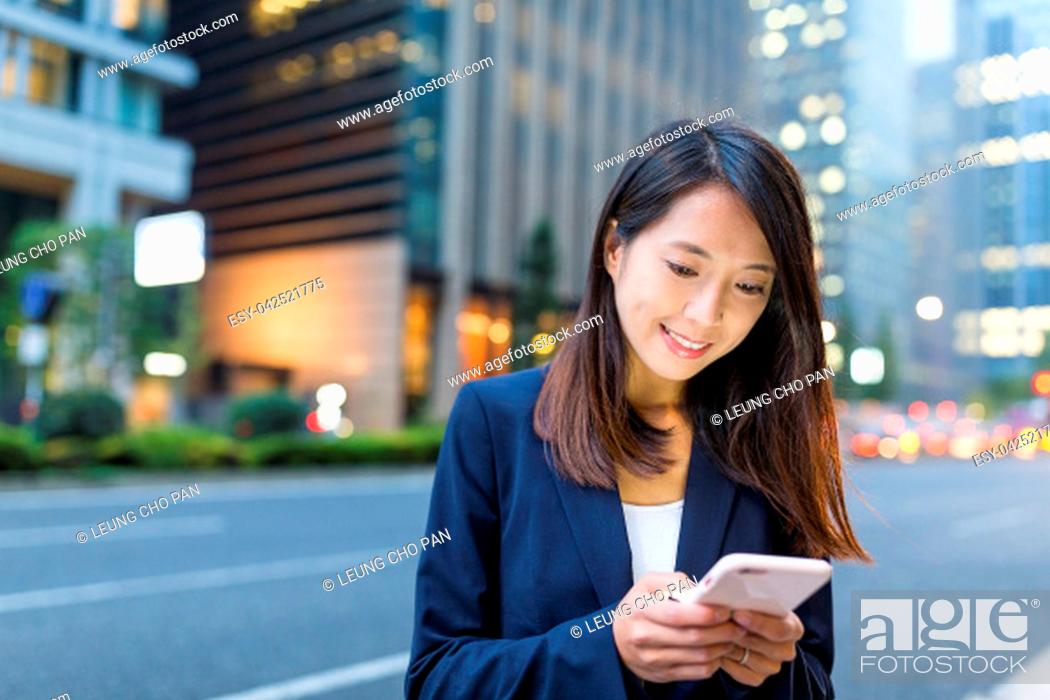 Stock Photo: Business woman use of mobile phone in Tokyo city at night.
