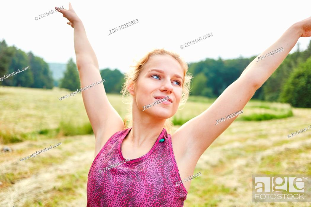Imagen: Junge Frau macht eine Yoga Übung in der Natur und streckt die Arme.