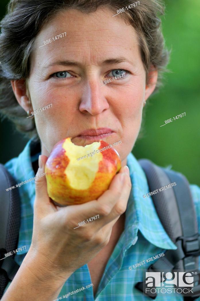 Stock Photo: A woman eats an apple during her hike.