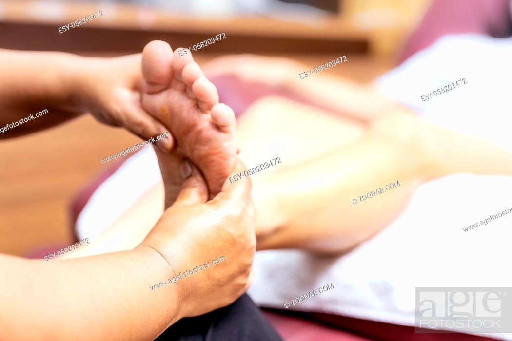 Stock Photo: Close up asian woman do foot massage at home with face mask while city lockdown for social distance due to coronavirus pandemic.