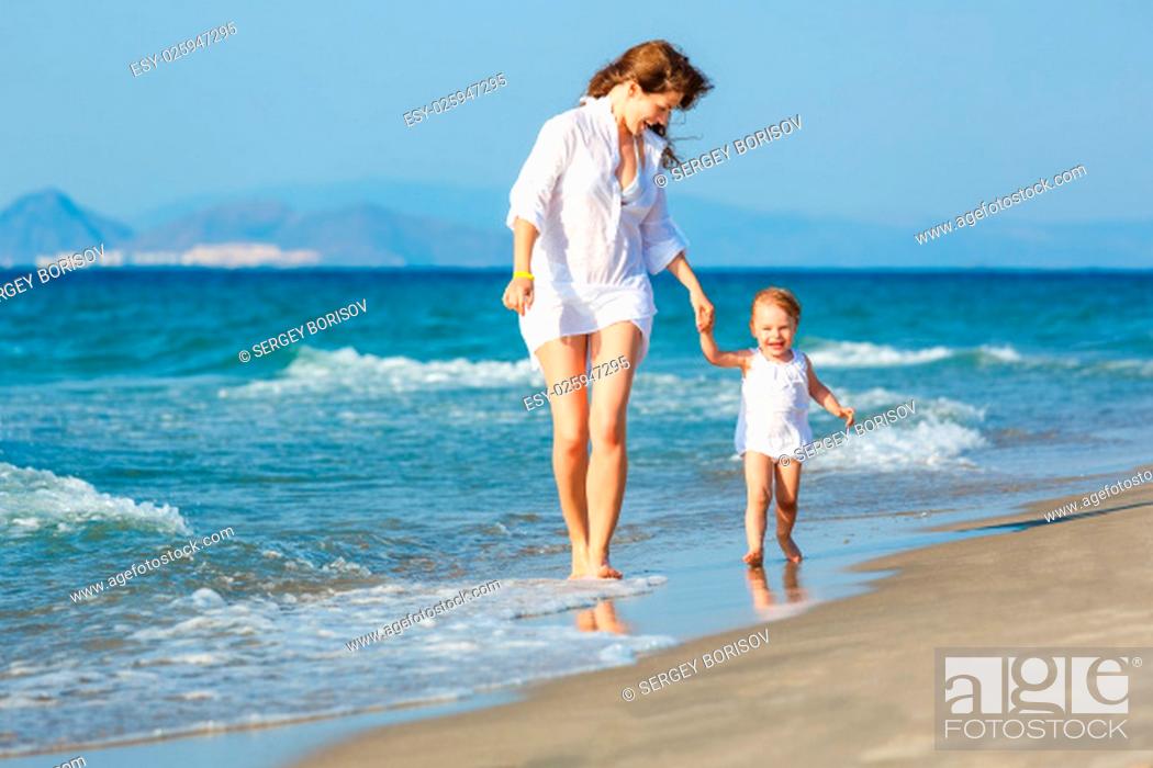 Photo de stock: Mother and little daughter walking on the beach.