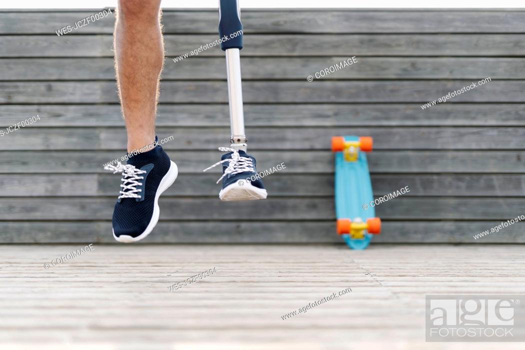 Stock Photo: Young man with artificial limb and foot jumping against wall.