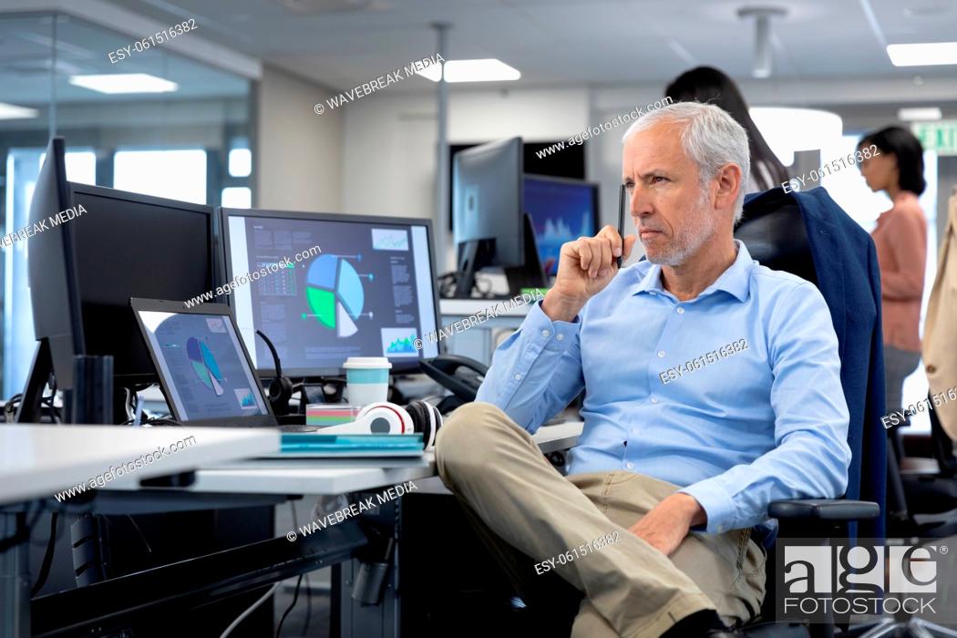 Stock Photo: Thoughtful Senior businessman sitting on his desk at modern office.