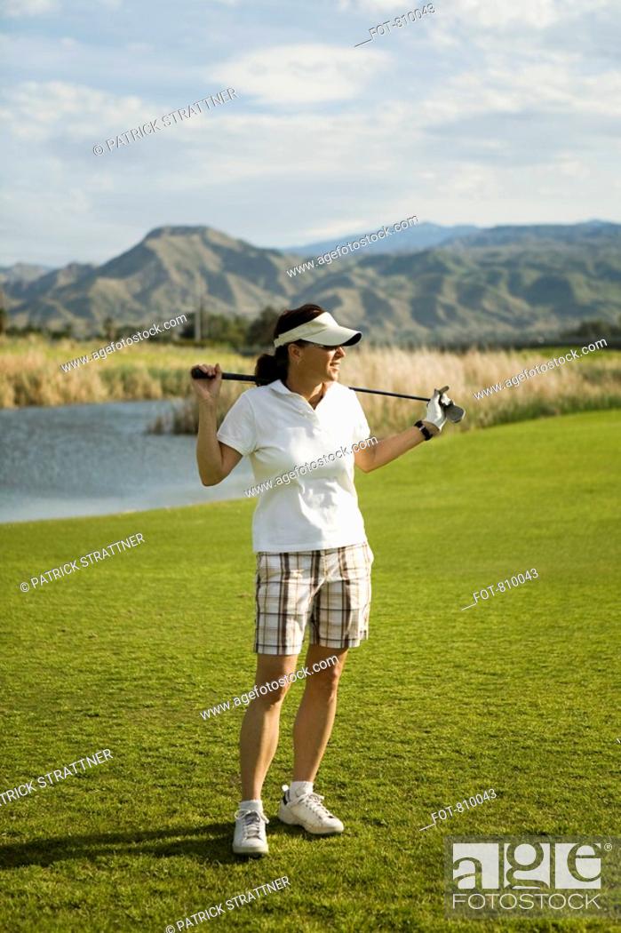 Stock Photo: A golfer standing with golf clubs across her shoulders, Palm Springs, California, USA.
