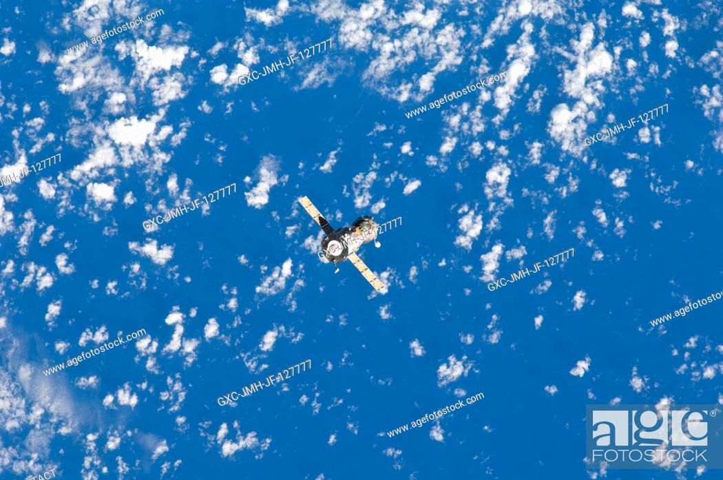 Stock Photo: Backdropped against a mixture of blue sky and clouds, the Soyuz TMA-21 spacecraft departs from the International Space Station and heads toward a landing in a.