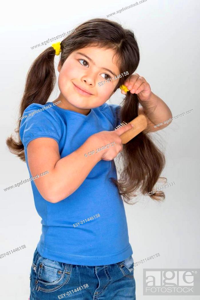 little girl smiling and combing hair. pretty girl wearing jeans and blue  t-shirt, Stock Photo, Picture And Low Budget Royalty Free Image. Pic.  ESY-011446158 | agefotostock