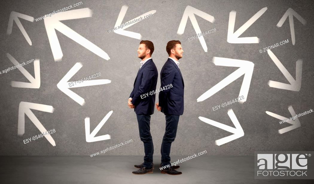 Stock Photo: Young conflicted businessman choosing between two directions with arrows around him.