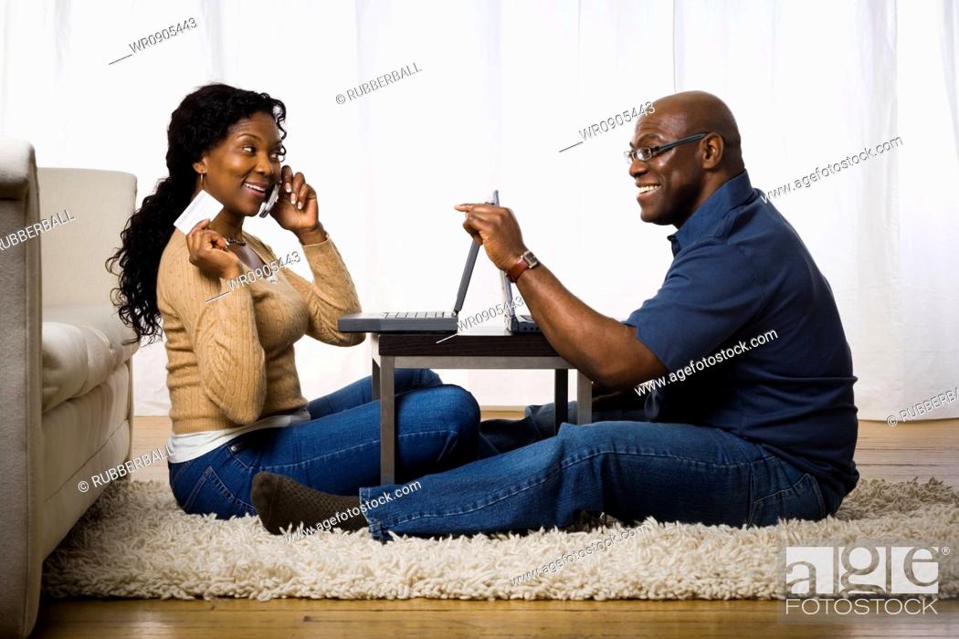 Stock Photo: Profile of a mature woman talking on a mobile phone with a man sitting in front of her.