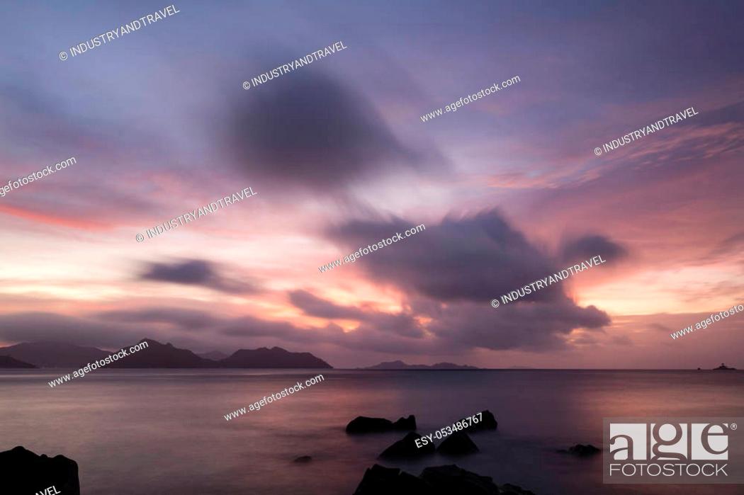 Photo de stock: Colorful sunset long exposure with view to Praslin from La Digue, Seychelles with granite rocks in the foreground.