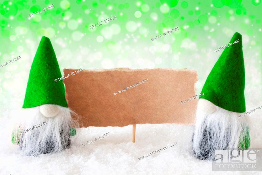 Stock Photo: Christmas Greeting Card With Two Green Gnomes. Sparkling Bokeh And Natural Background With Snow. Copy Space For Advertisement.