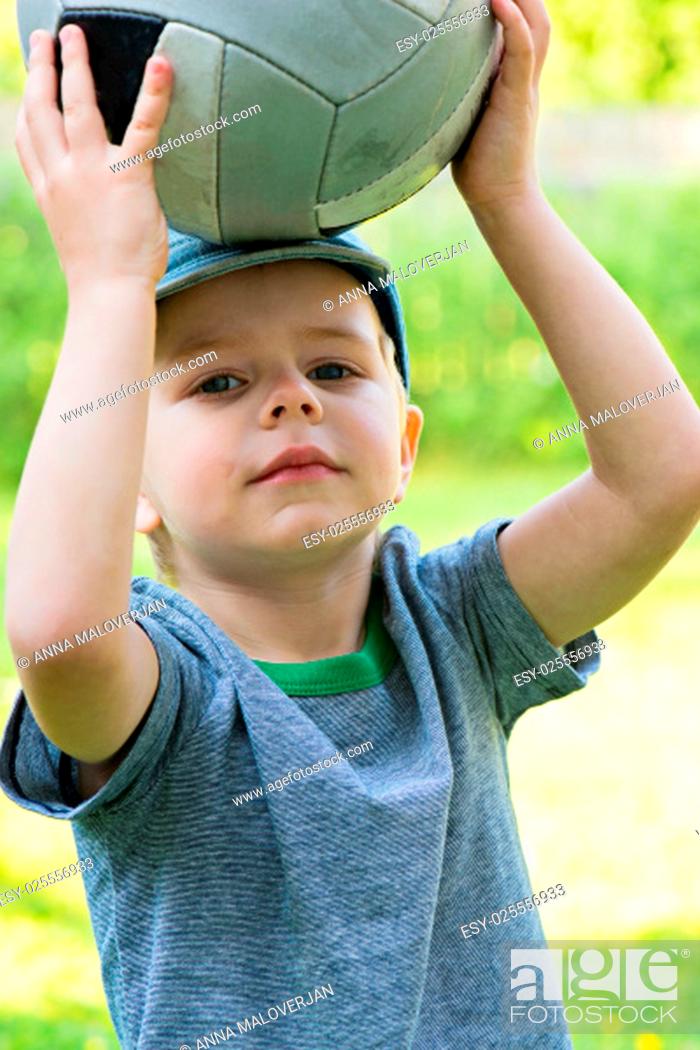 Stock Photo: Little boy holding sport ball over his head.