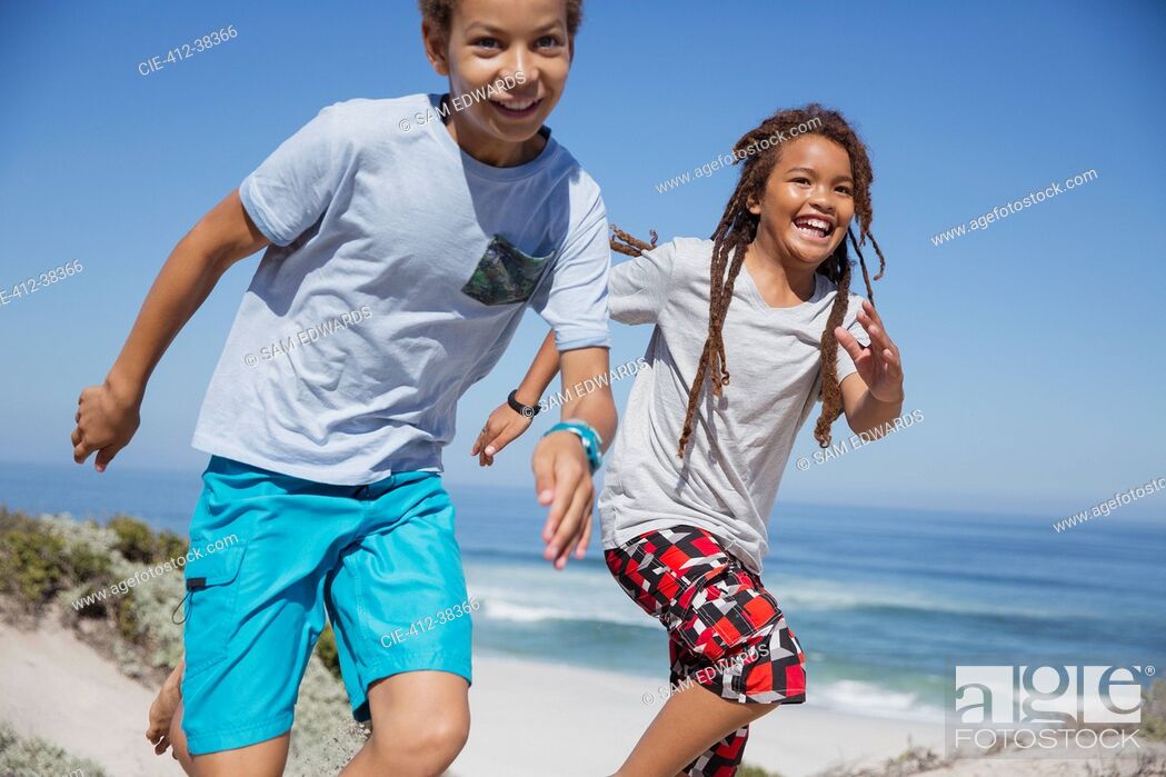 Stock Photo: Playful brother and sister running on sunny summer beach.