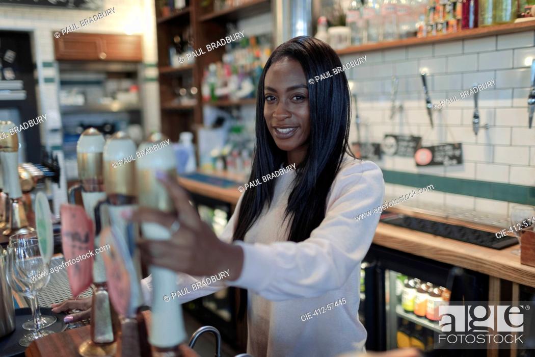 Photo de stock: Portrait happy young female bartender behind bar.