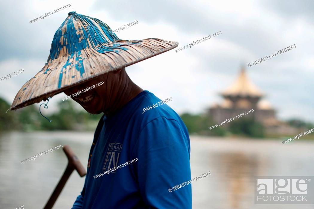 Stock Photo: A ferryman is standing at the shore of the Sarawak River in front of the Sarawak State Legislative Assembly Building in Kuching, Malaysia, 21 October 2014.