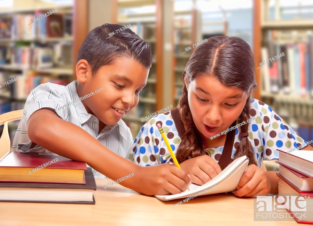 Stock Photo: Hispanic boy and girl having fun studying together in the library.