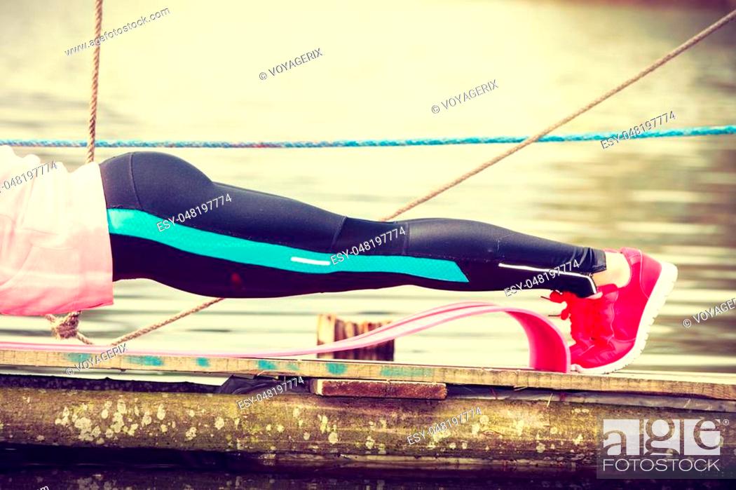 Stock Photo: Sports and activities concept. Slim fit attractive woman exercising stretching outdoor. Young motivated girl training in sporty clothes on lake shore.