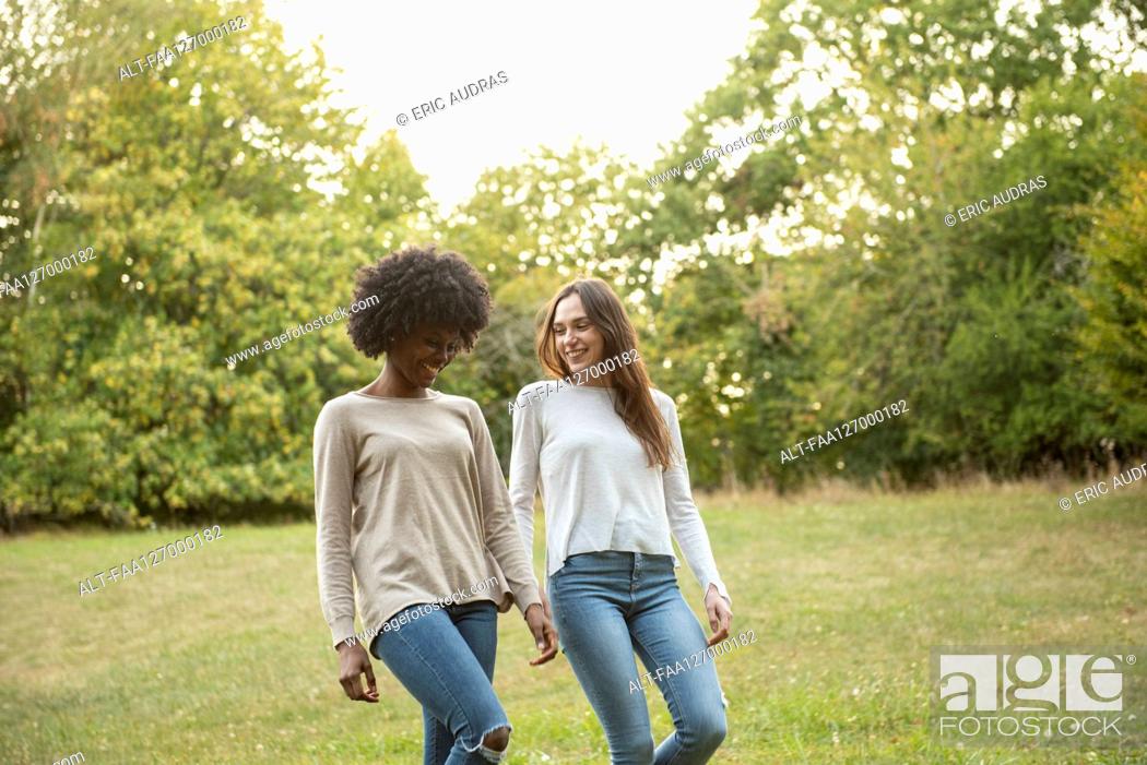 Photo de stock: Smiling young female friends walking in park.