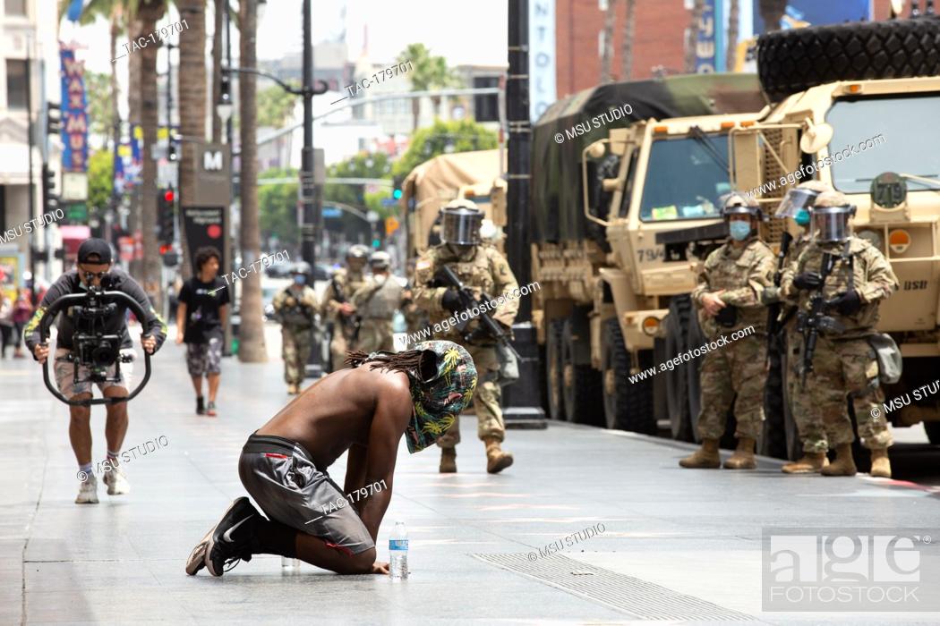 Photo de stock: Los Angeles, CA - June 2, 2020: A man prays in front of National Guard during the George Floyd Black Lives Matter Protest on June 2.