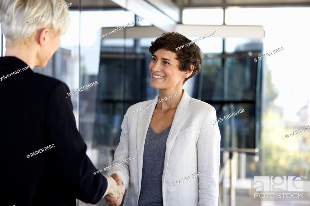 Stock Photo: Two businesswomen shaking hands in office.