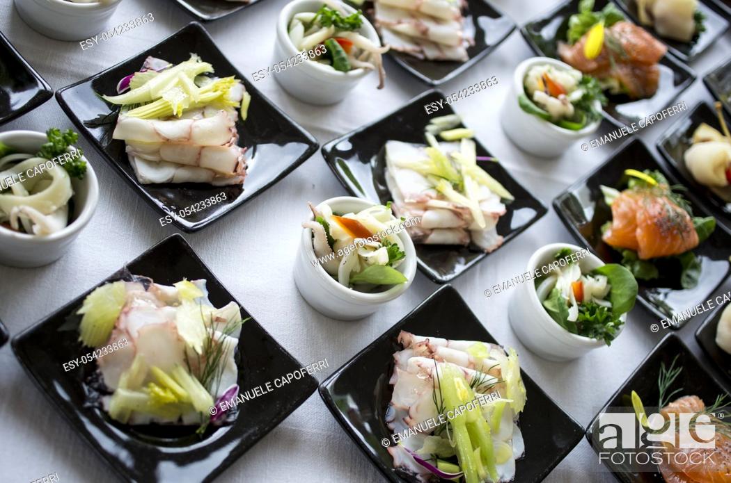 Stock Photo: Fish entrée served on white plates and black dishes.