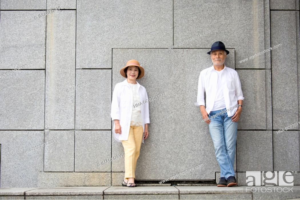 Stock Photo: Senior couple standing against wall.