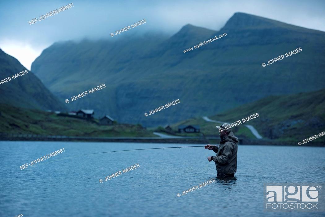 Stock Photo: Man fly fishing in lake.