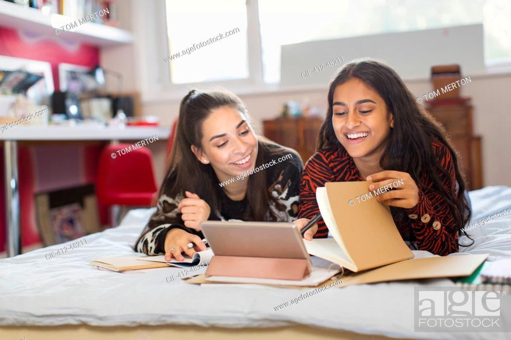 Stock Photo: Teenage girl friends studying, doing homework on bed.