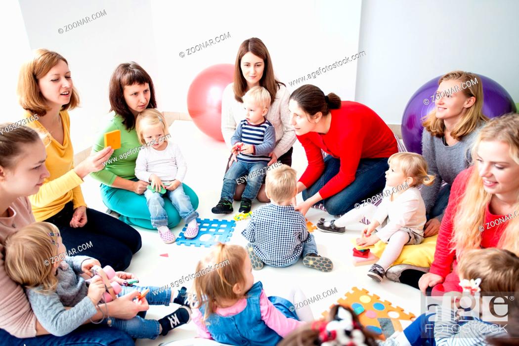 Stock Photo: Children with mothers sit in a circle and study colors, numbers and figures in the kindergarten.