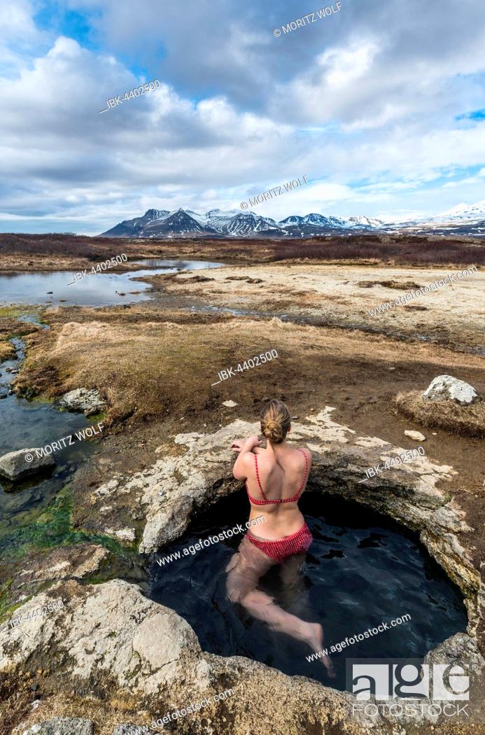 Stock Photo: Young woman in hot spring looking towards mountains, Eyjar og Miklaholt, Western Region, Iceland.