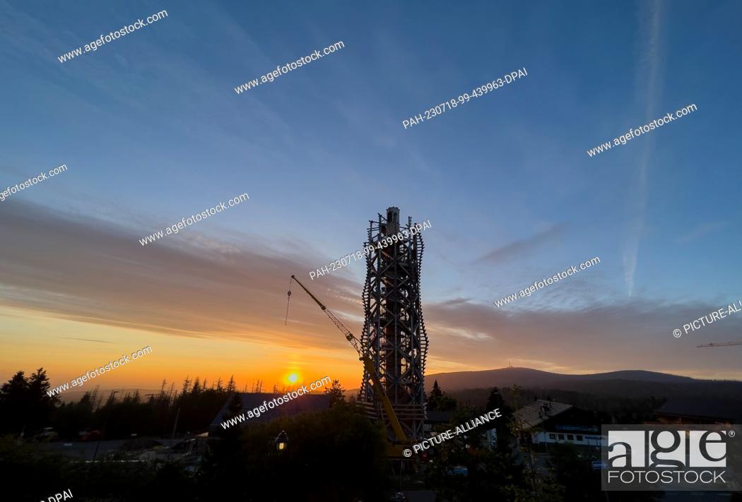 Stock Photo: 18 July 2023, Lower Saxony, Torfhaus: The sun rises behind the Harz Tower in the Harz National Park. Construction of the 65-meter-high observation tower.