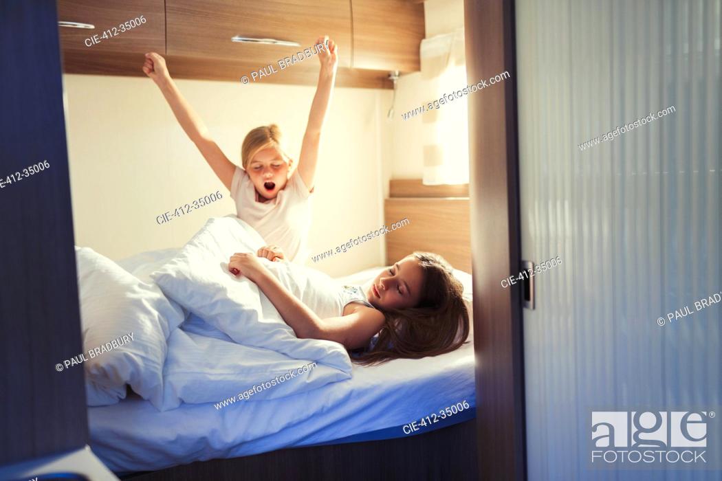 Stock Photo: Sisters waking and stretching on bed in motor home.
