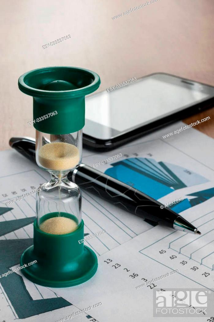 Stock Photo: Hourglass on the table businessman, as background.