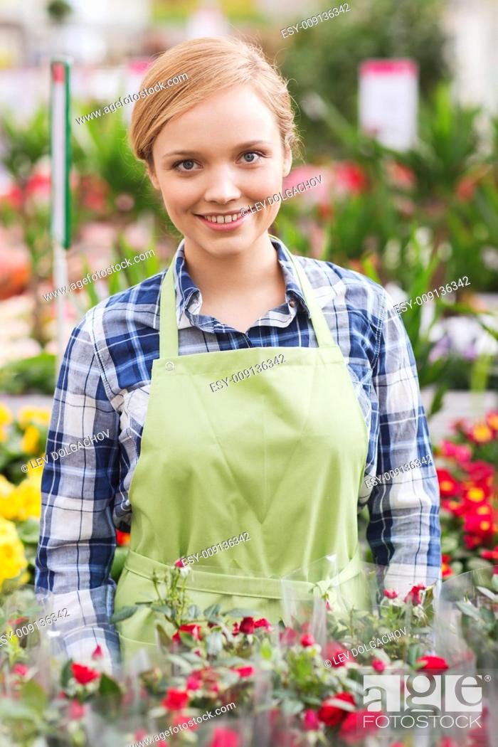 Stock Photo: people, gardening and profession concept - happy woman with flowers in greenhouse.
