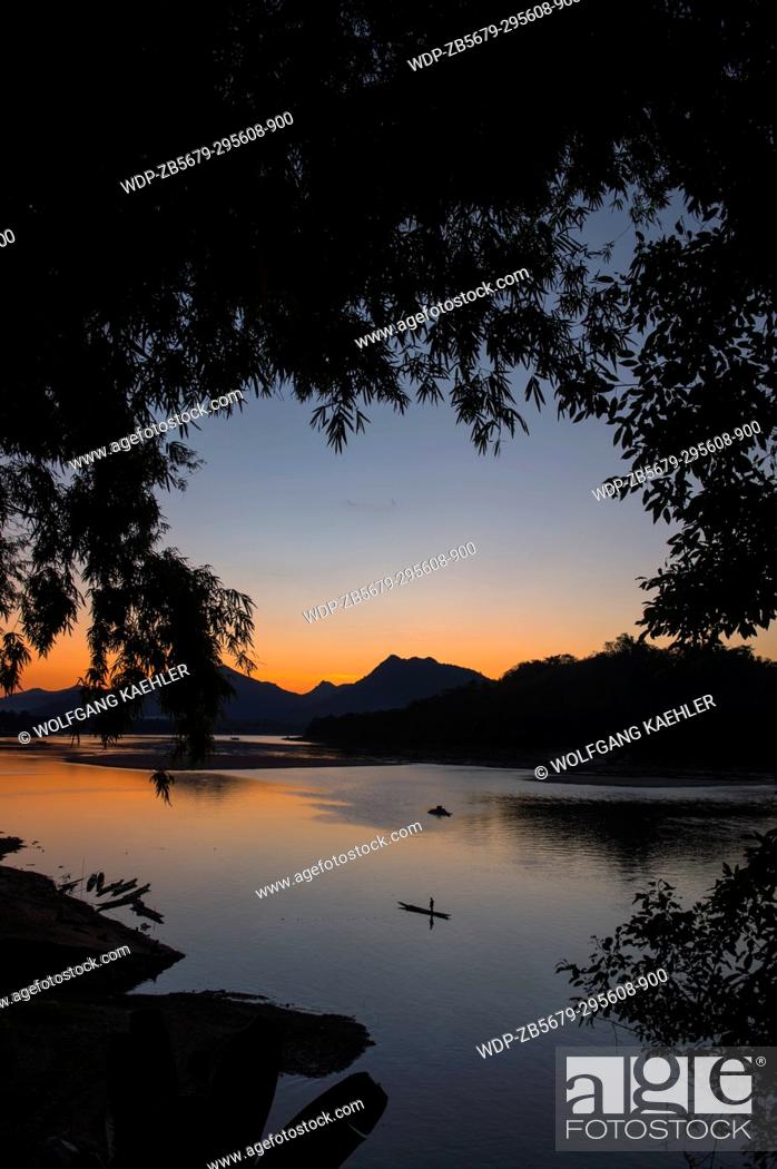 Stock Photo: View of the Mekong River with a fisherman in a boat after sunset near the UNESCO world heritage town of Luang Prabang in Central Laos.