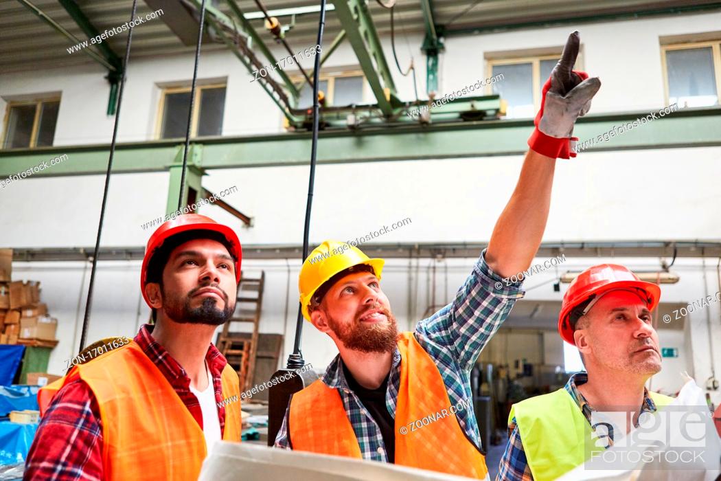 Stock Photo: Handwerker und Bauarbeiter diskutieren mit Bauplan die Sanierung der Metallfabrik.