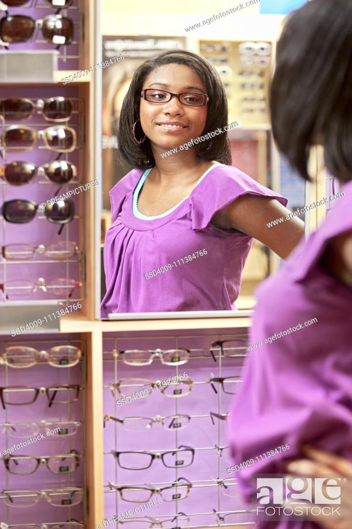 Stock Photo: African American girl trying on eyeglasses in store.