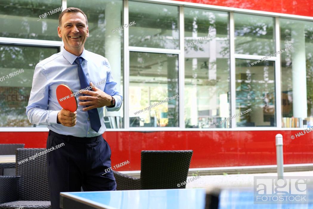 Stock Photo: Smiling business person playing table tennis at creative office.