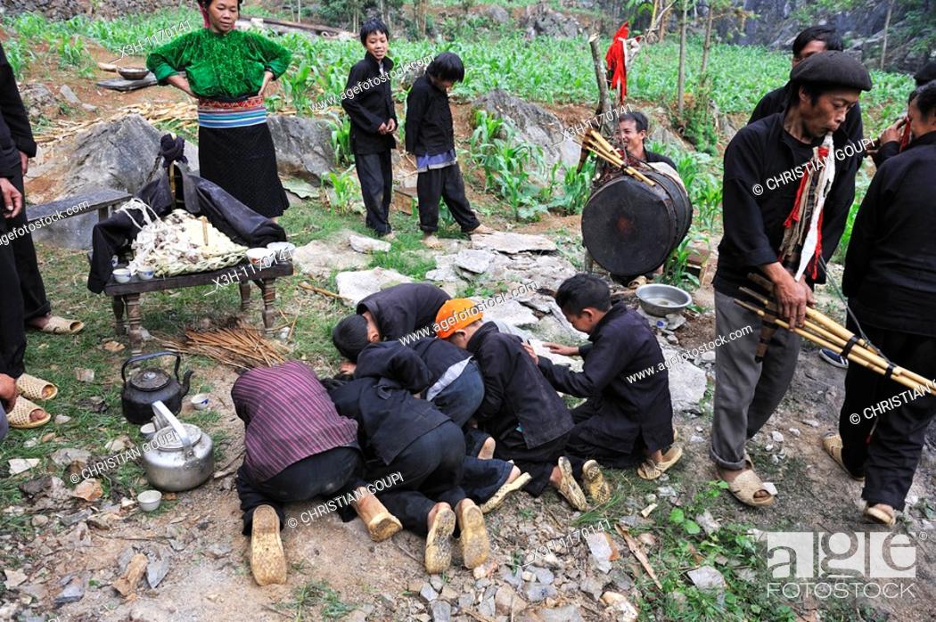 Stock Photo: H'mong boys prostating themselves before the altar for deceased during funeral in a village around Sa Phin, Ha Giang province, Northern Vietnam, southeast asia.