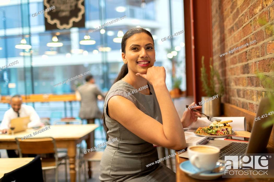 Stock Photo: Confident businesswoman eating lunch and working in cafe.