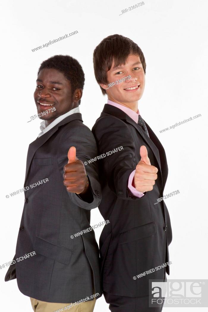 Stock Photo: Two young businessmen standing back to back and making a thumbs-up gesture.