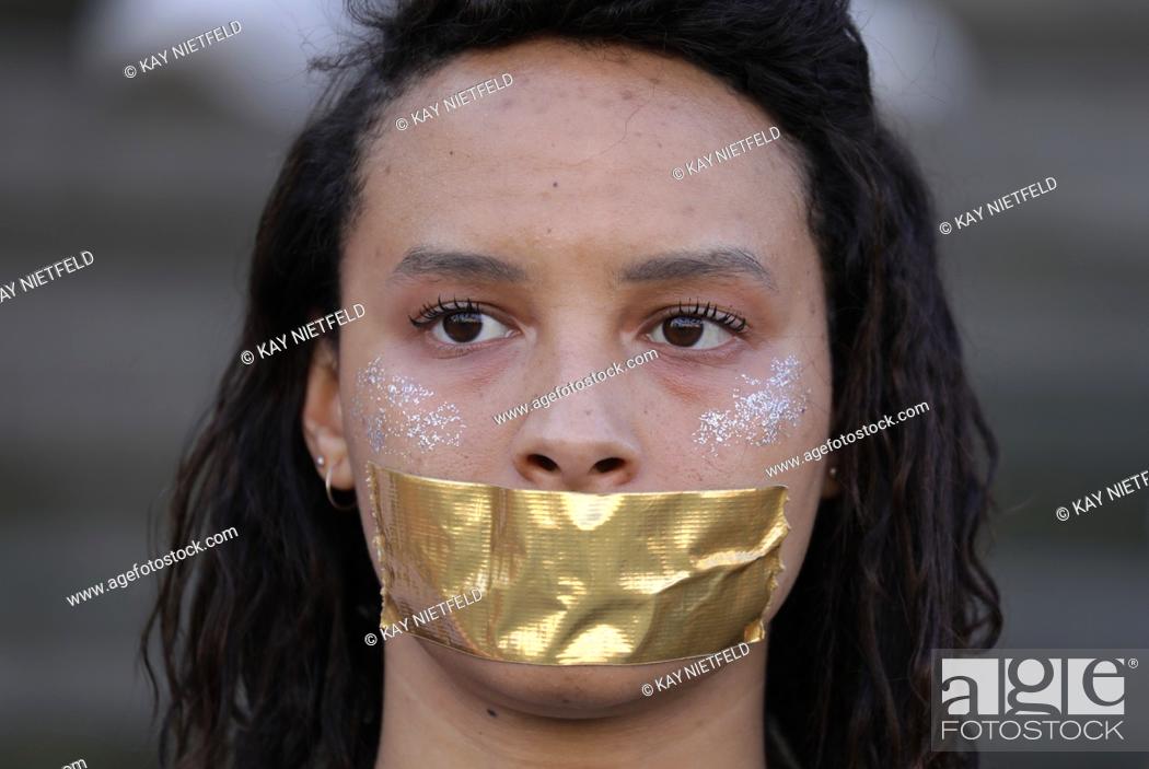 Stock Photo: A students pasted a golden piece of paper in front of her mouth during a protest action for more democracy before a campaign event on the German federal.